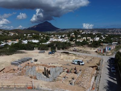 Vista aérea de la construcción de una villa en Jávea, mostrando los cimientos y estructuras iniciales. Rodeada de zona residencial con vistas a la montaña del Montgó.
