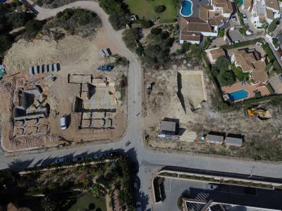 Vista aérea de un solar en desarrollo en Jávea, con cimentaciones de hormigón para nuevas villas y parcelas excavadas junto a viviendas existentes con piscinas privadas.