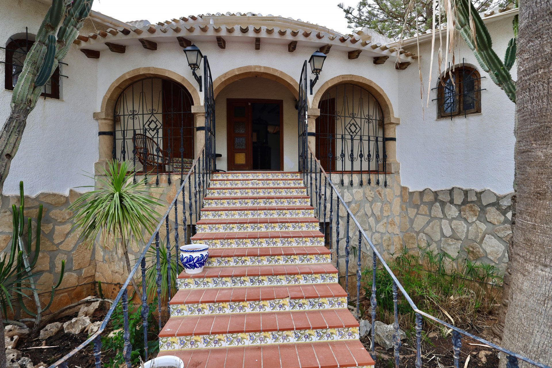 Entrada principal de la villa con escalones de terracota y detalles florales.
