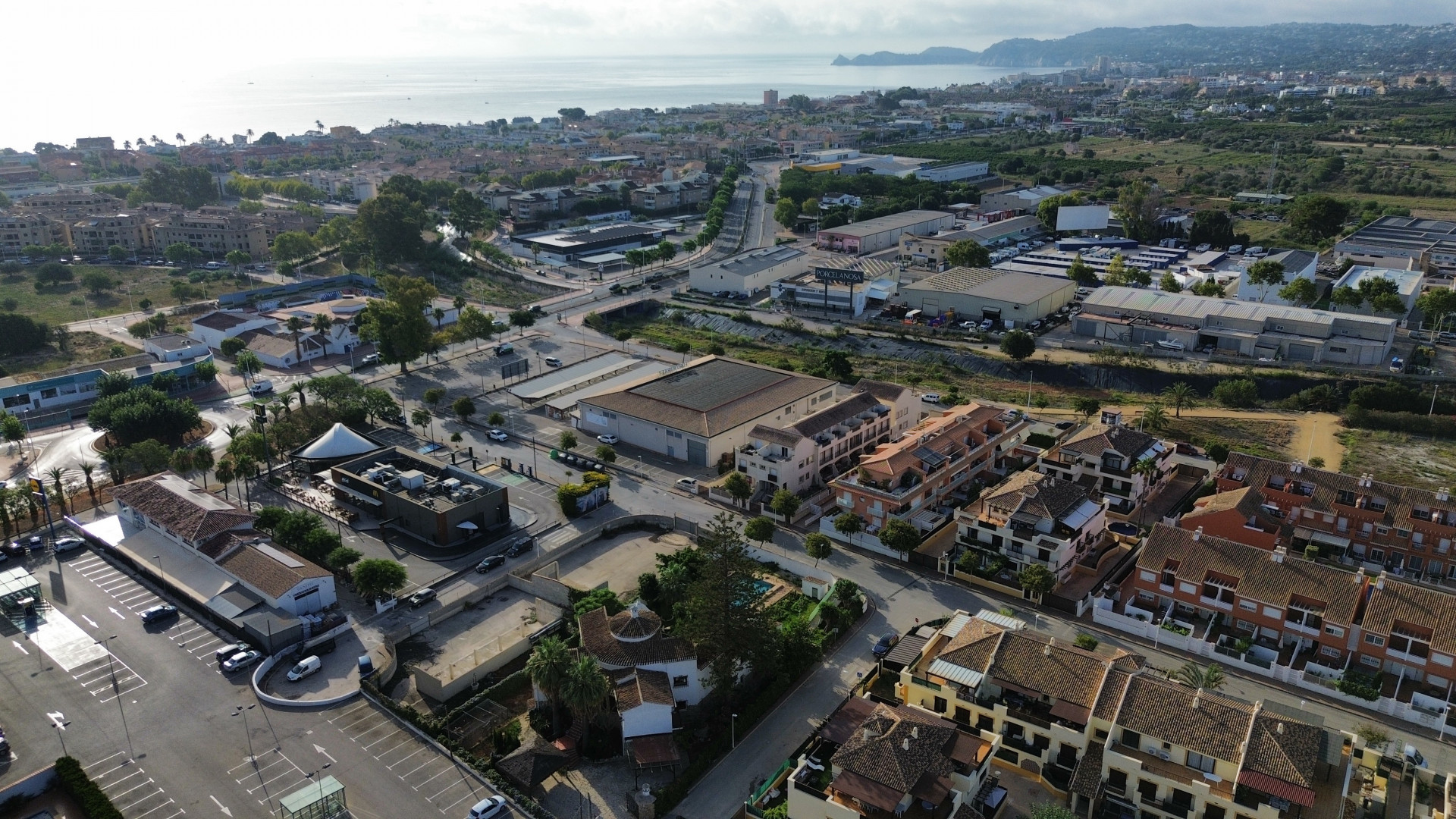 Vista aérea de Jávea con edificios residenciales, comerciales y el mar Mediterráneo al fondo.
