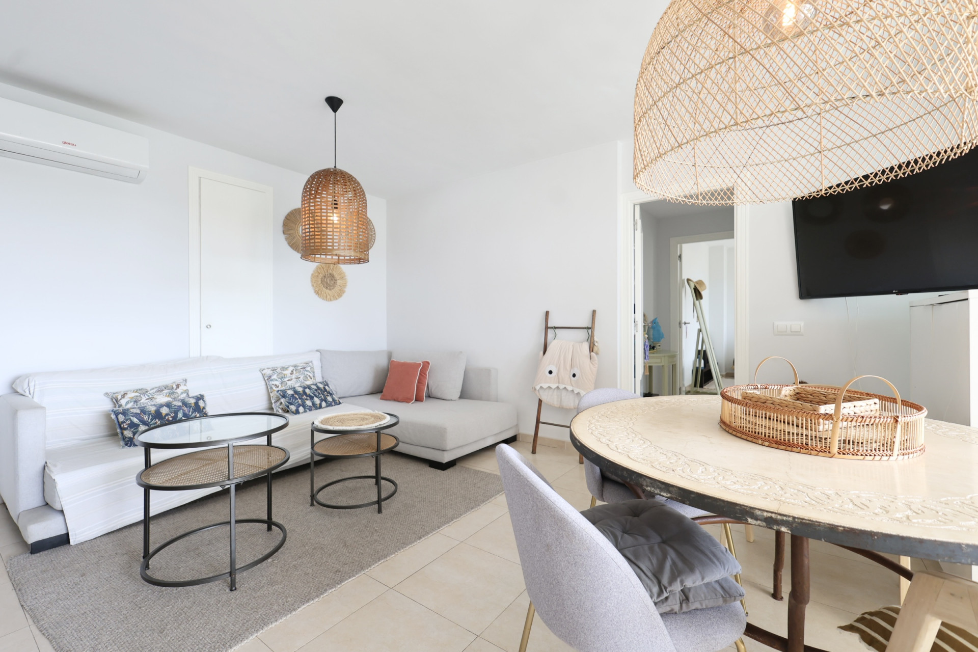 Salón comedor luminoso con sofá esquinero, lámparas de mimbre y mesa de centro de diseño.