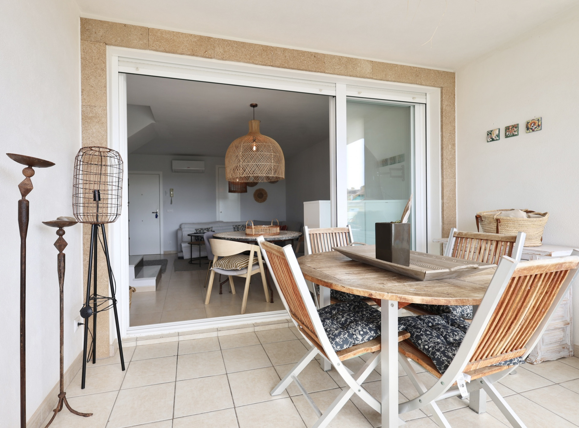 Terraza cubierta con mesa de madera y sillas plegables con cojines estampados.