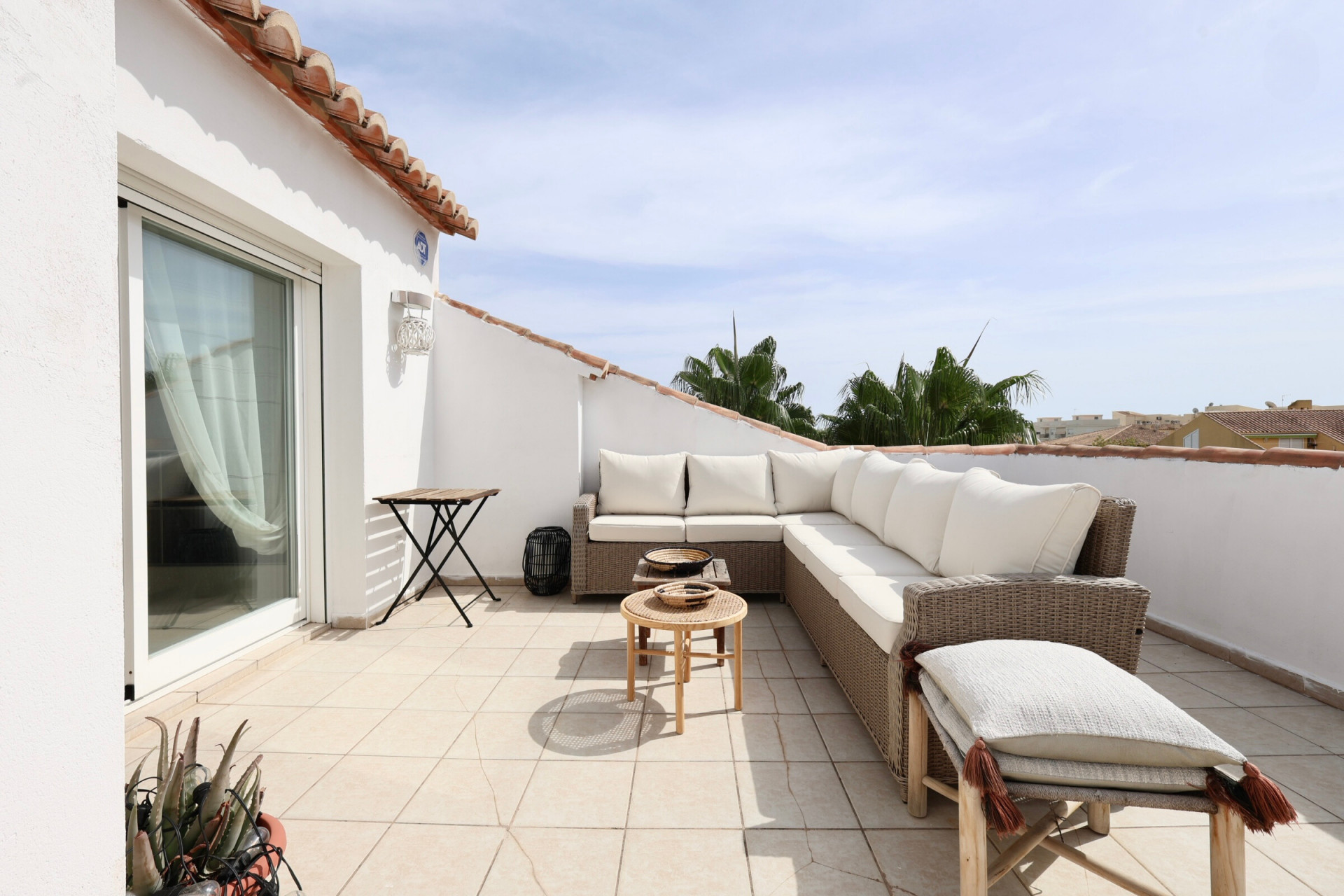 Terraza soleada con mobiliario de ratán y vistas parciales al horizonte.