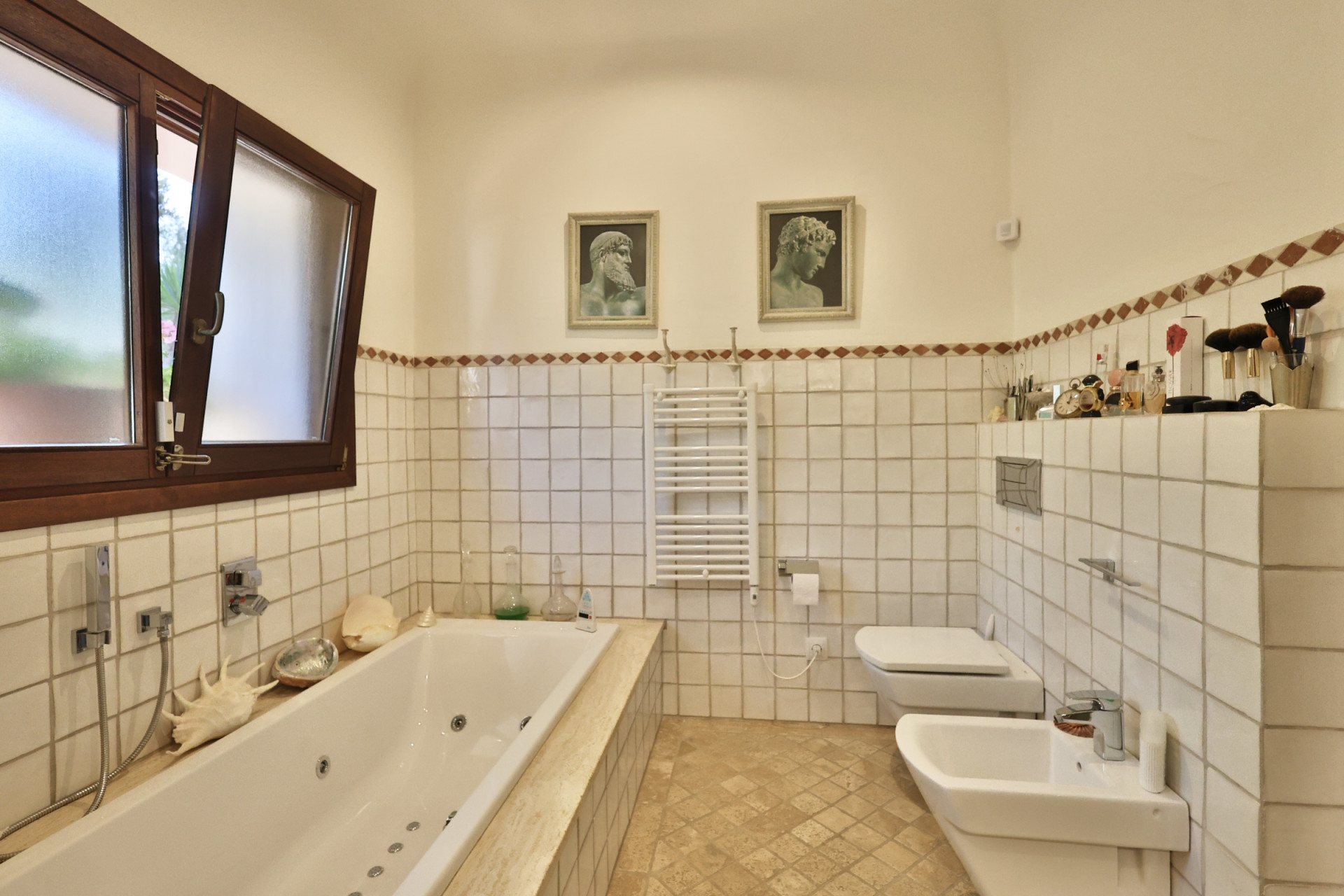 Baño principal con bañera de hidromasaje integrada, ventana de madera con cristal esmerilado y azulejos blancos con cenefa en tonos tierra. Baño principal con bañera de hidromasaje integrada, ventana de madera con cristal esmerilado y azulejos blancos con cenefa en tonos tierra.