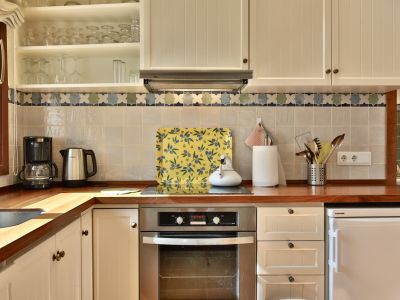 Cocina con encimera de madera y armarios crema, destacando un horno integrado y azulejos con cenefa decorativa.