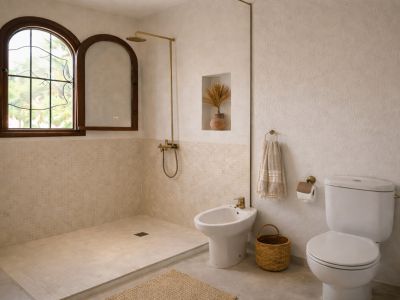 Baño luminoso con ducha de obra y azulejos de mosaico beige. Ventana arqueada de madera con vistas al exterior, grifería de latón y paredes texturizadas.
