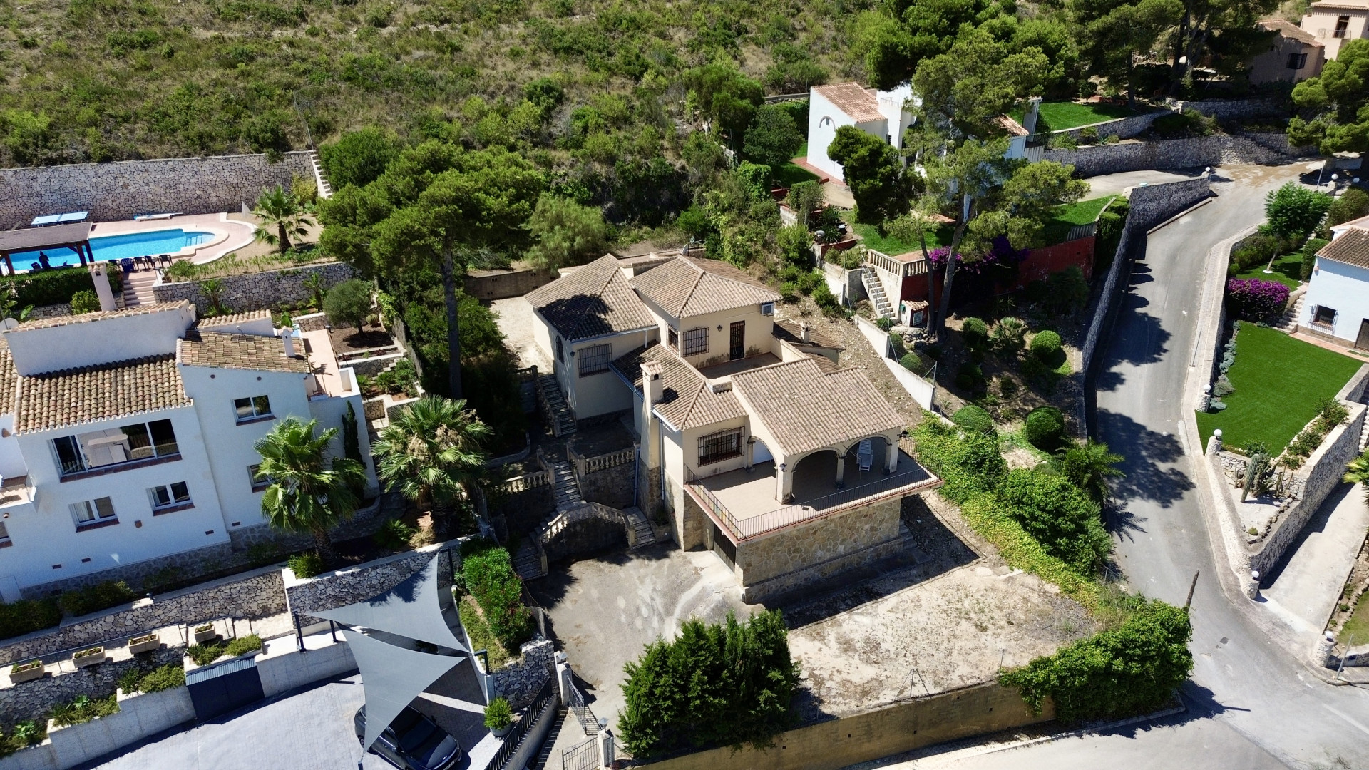 Vista aérea de la villa de varios niveles con tejados tradicionales, múltiples terrazas y áreas ajardinadas en pendiente, integrada en la vegetación mediterránea. Vista aérea de la villa de varios niveles con tejados tradicionales, múltiples terrazas y áreas ajardinadas en pendiente, integrada en la vegetación mediterránea.