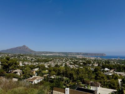 Vista panorámica de Jávea con el imponente Montgó, el mar Mediterráneo y el paisaje urbano arbolado bajo un cielo claro.