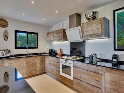 Cocina equipada con armarios de madera rústica y encimeras negras. La ventana sobre el fregadero ofrece vistas a la vegetación exterior.