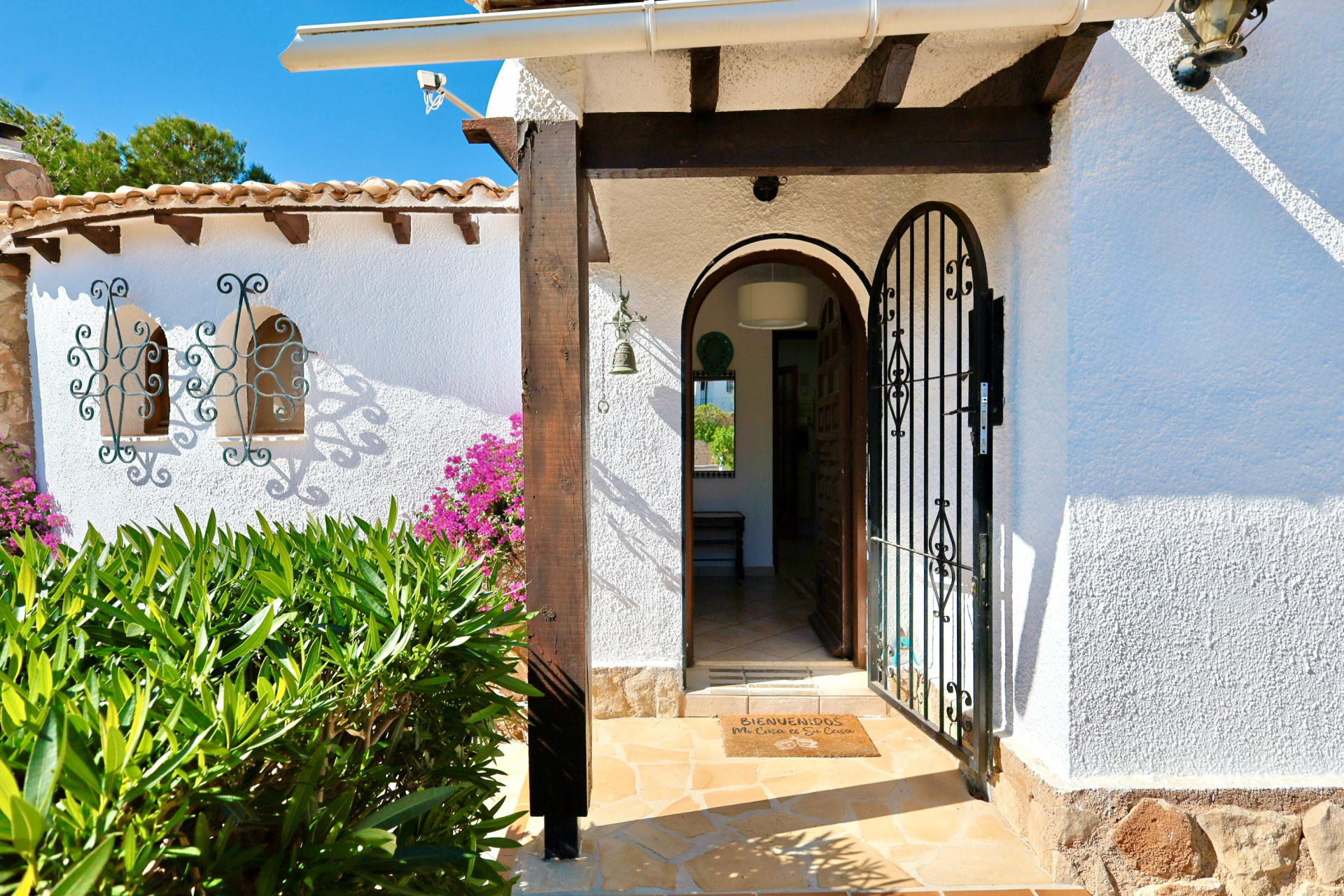Entrada principal con puerta de hierro forjado y felpudo de bienvenida.