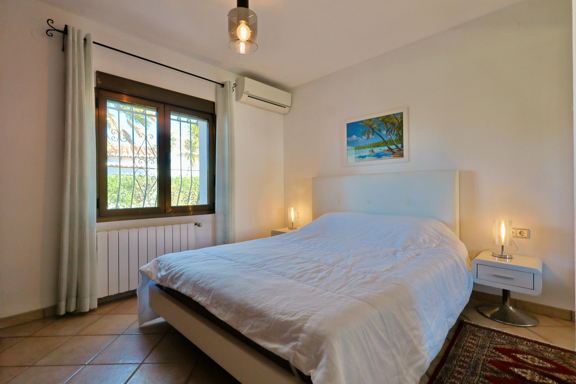 Luminoso dormitorio con cama doble, mesitas de noche modernas y ventana con vistas al exterior.