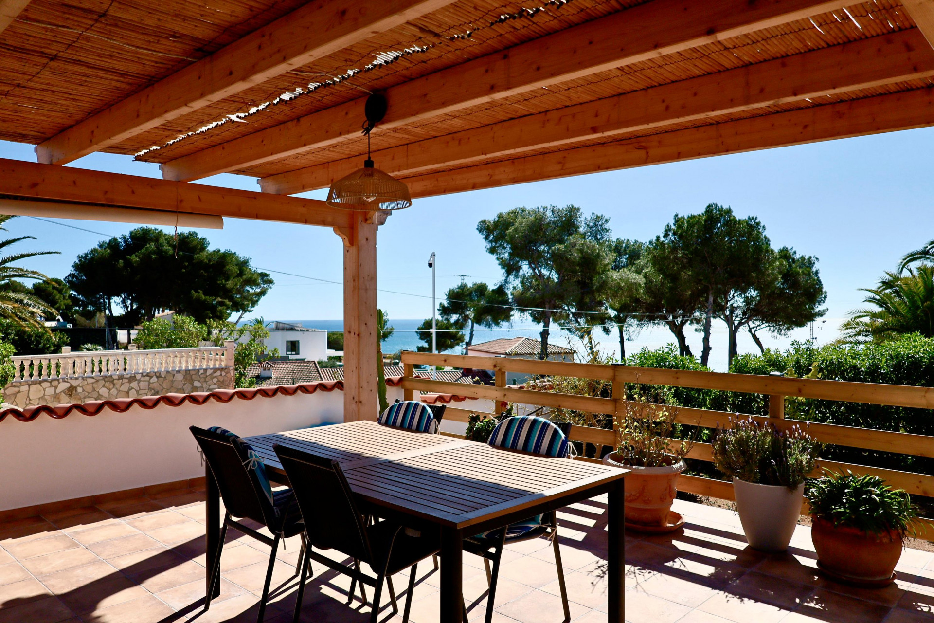 Terraza cubierta con mesa de comedor y vistas al mar en Jávea.