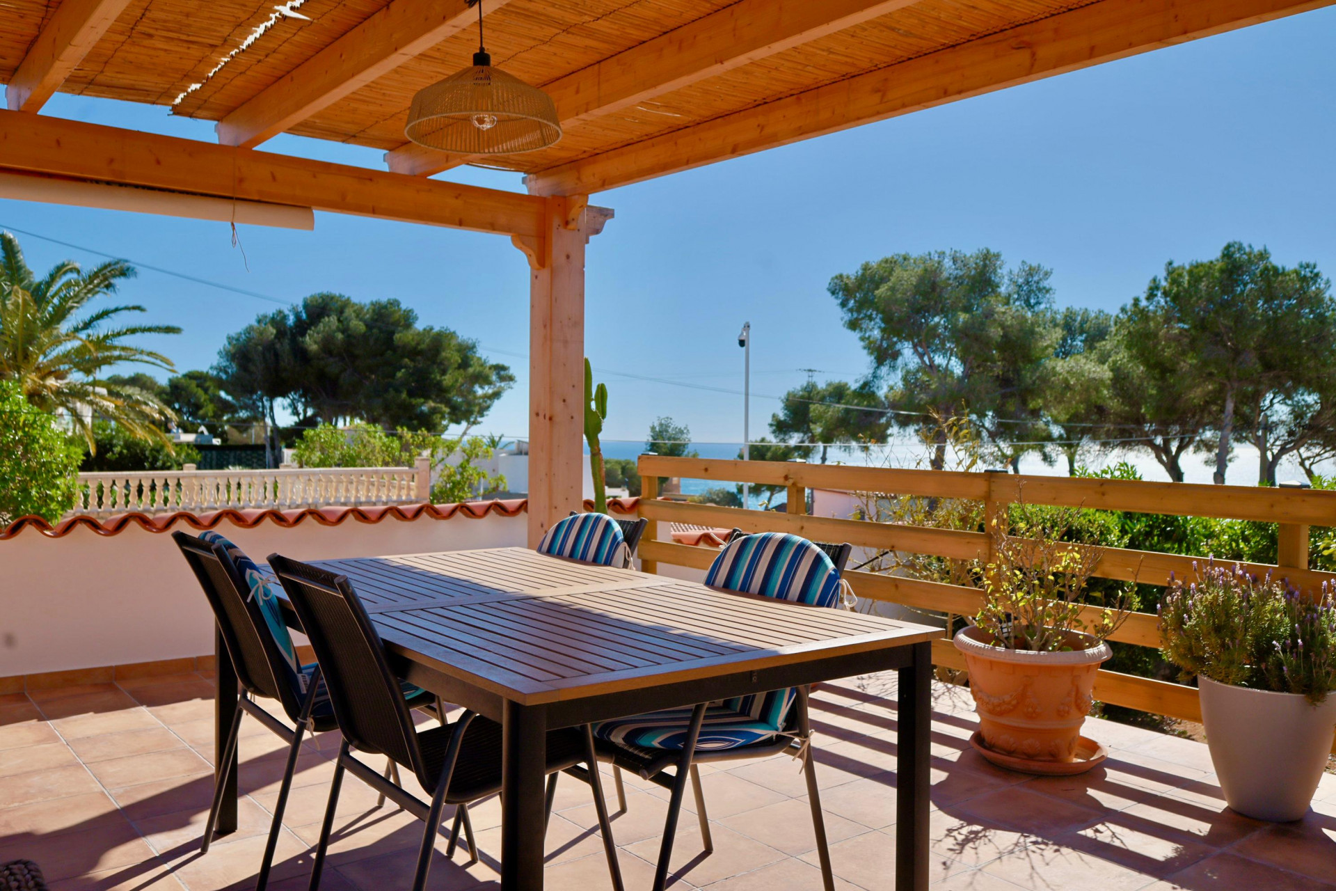 Terraza cubierta con mesa de comedor y vistas al mar Mediterráneo.