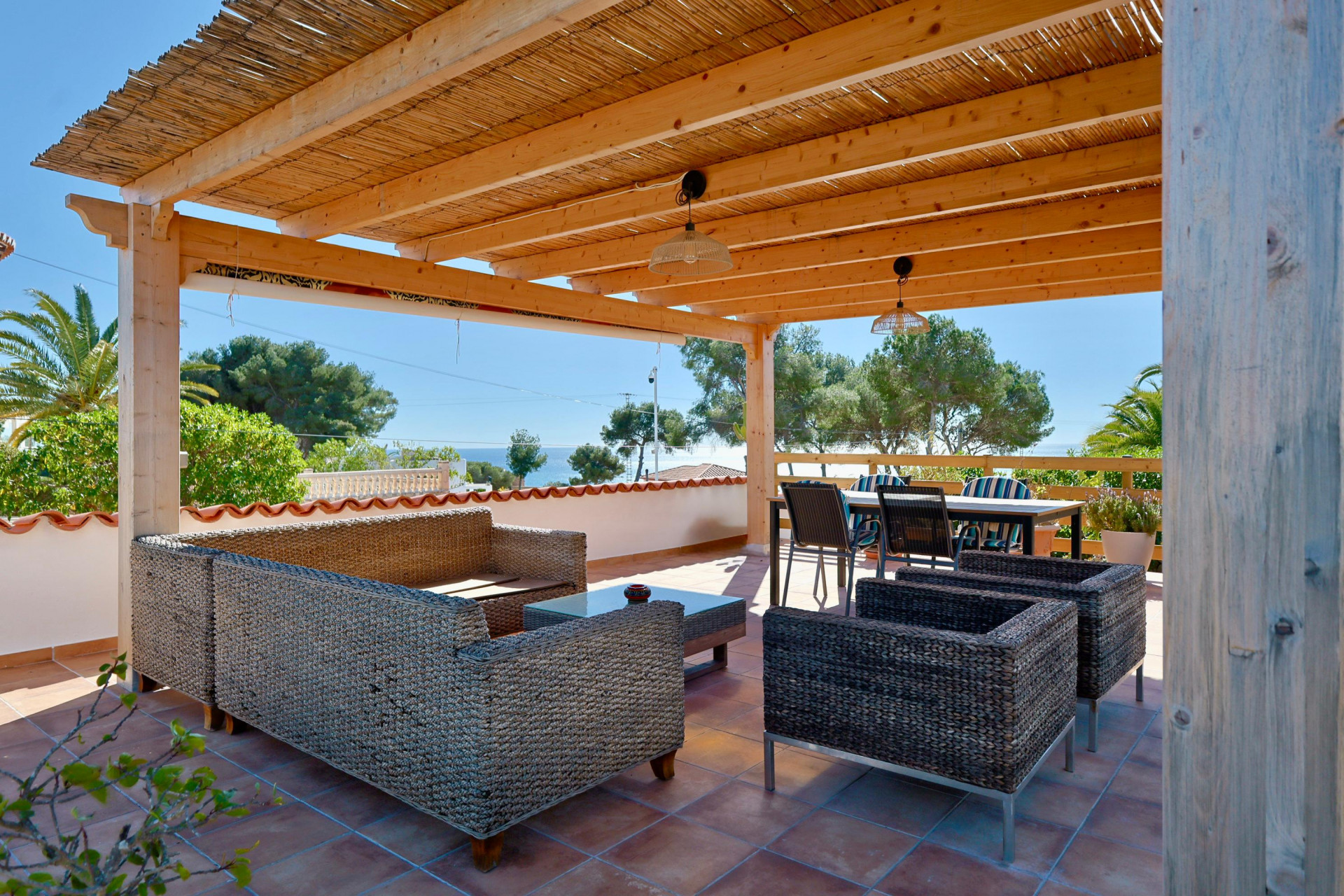 Terraza cubierta con muebles de ratán y vistas al mar.