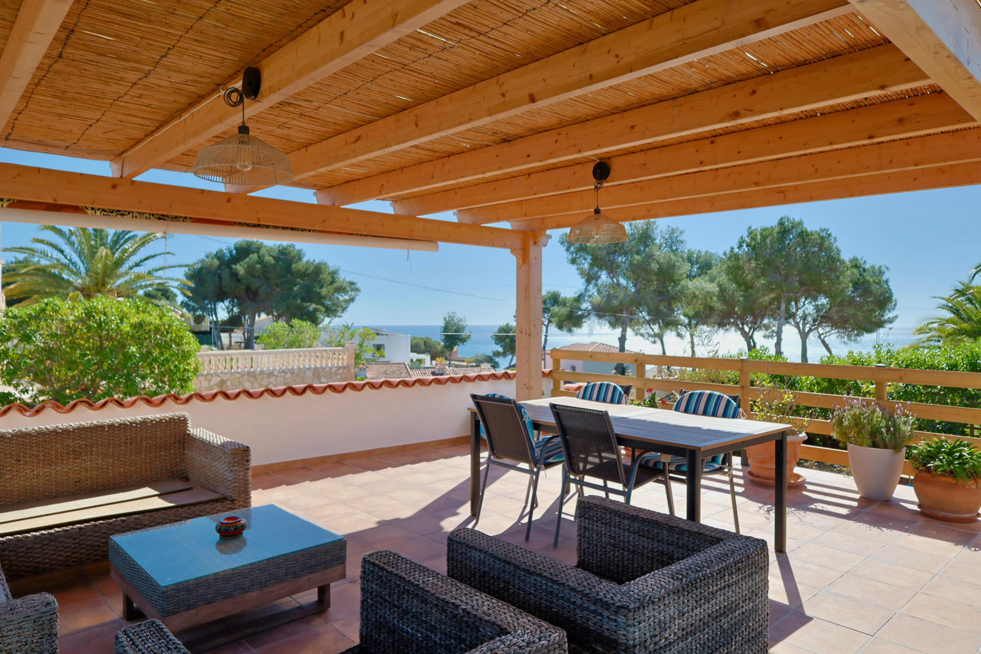 Terraza cubierta con vistas al mar y muebles de ratán.