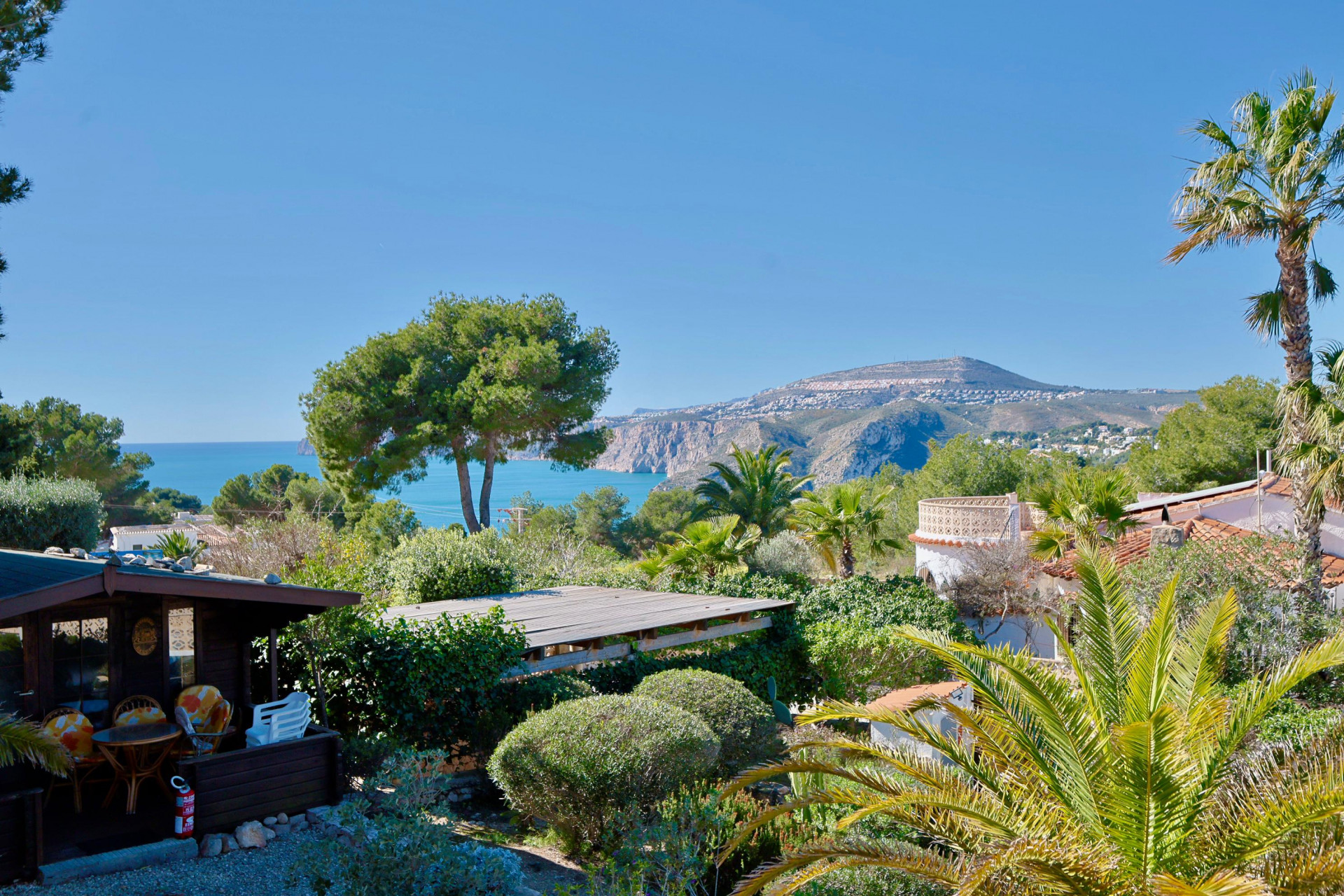 Vista panorámica de Jávea con cabaña de madera y vegetación exuberante.
