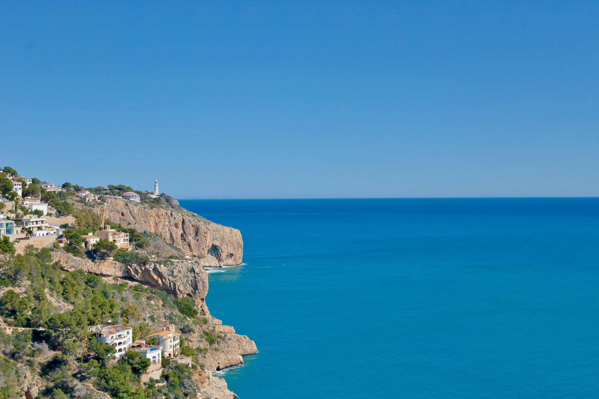 Vista panorámica de la costa rocosa y el mar Mediterráneo desde Jávea, con casas blancas en la ladera.