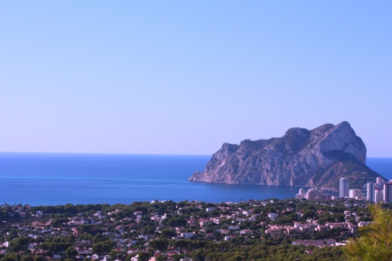 Vista panorámica del Peñón de Ifach y el mar Mediterráneo desde una posición elevada, rodeada de vegetación autóctona y el perfil costero de Calpe.