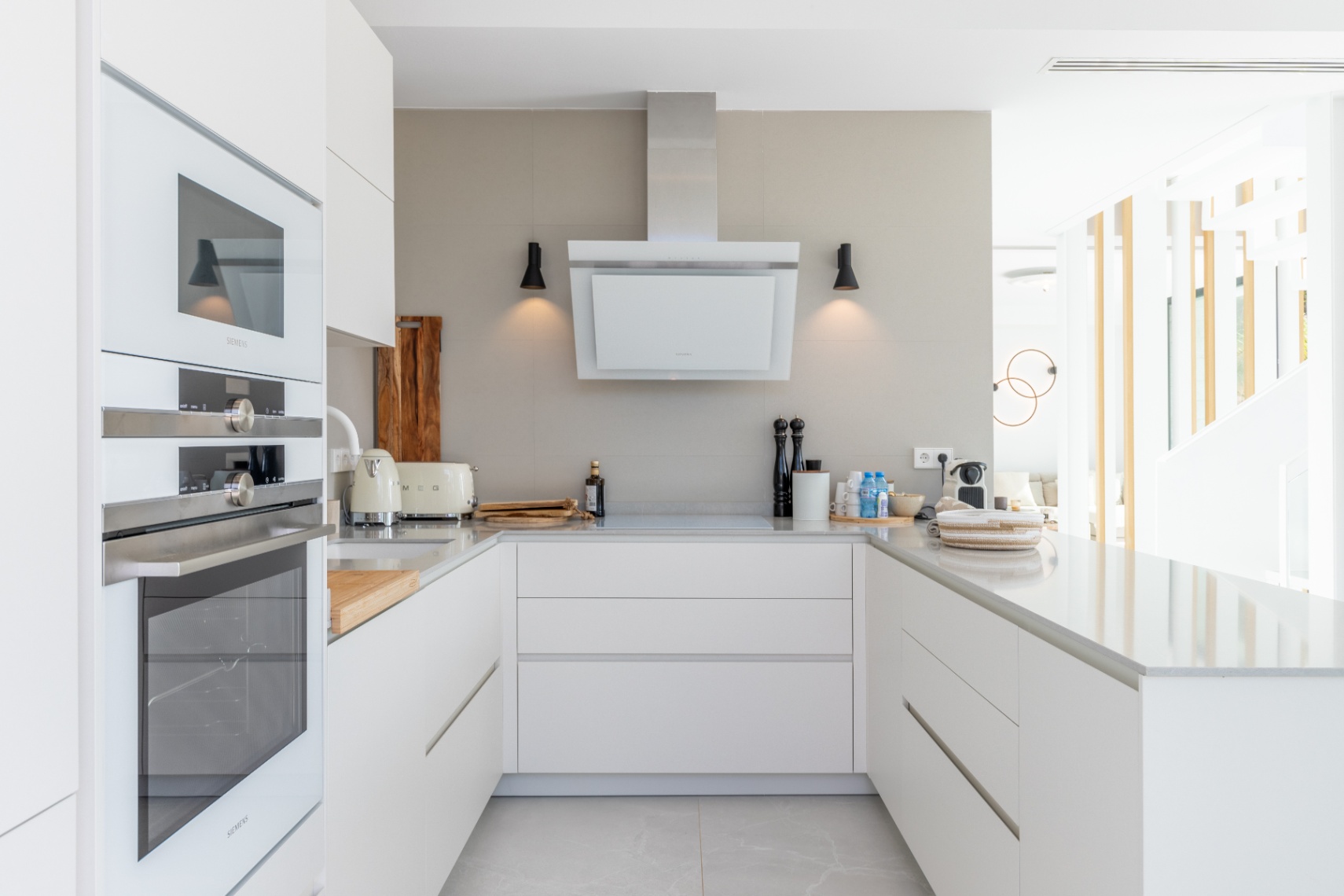 Cocina moderna con electrodomésticos Siemens, encimera de piedra clara y campana extractora minimalista.