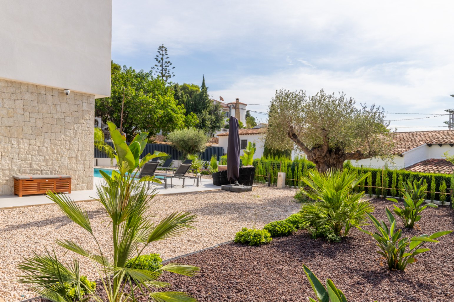 Jardín mediterráneo con grava, piscina y tumbonas en La Fustera, Benissa.