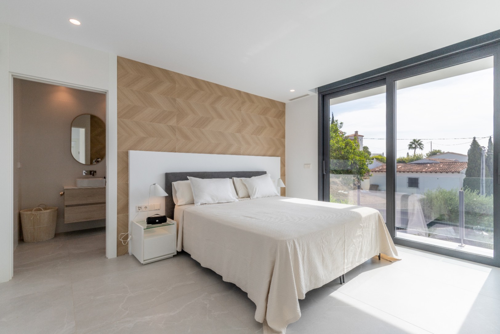 Luminoso dormitorio con pared decorativa de espiga y acceso al baño en suite. Ventanal con vistas.