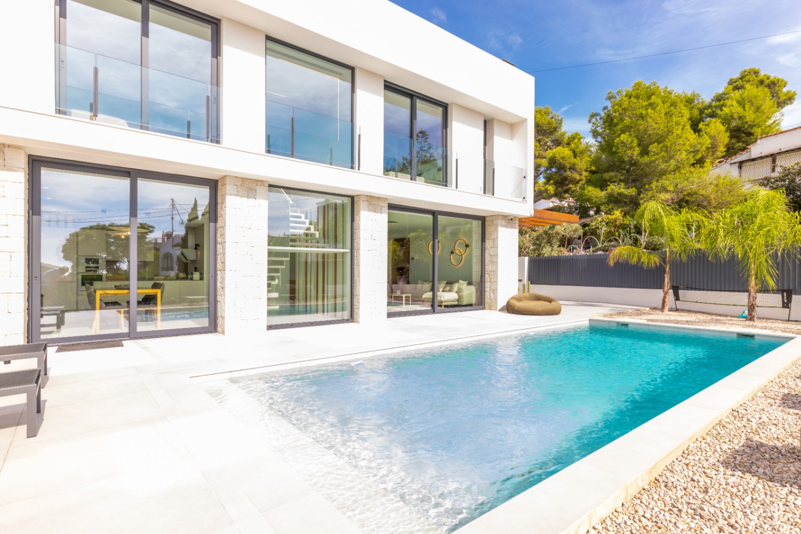 Vista de la piscina privada, la terraza de baldosas y la fachada moderna de la villa en Benissa.
