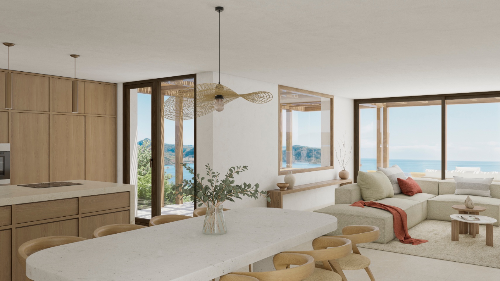 Interior luminoso con cocina abierta, isla de piedra y vistas al mar.