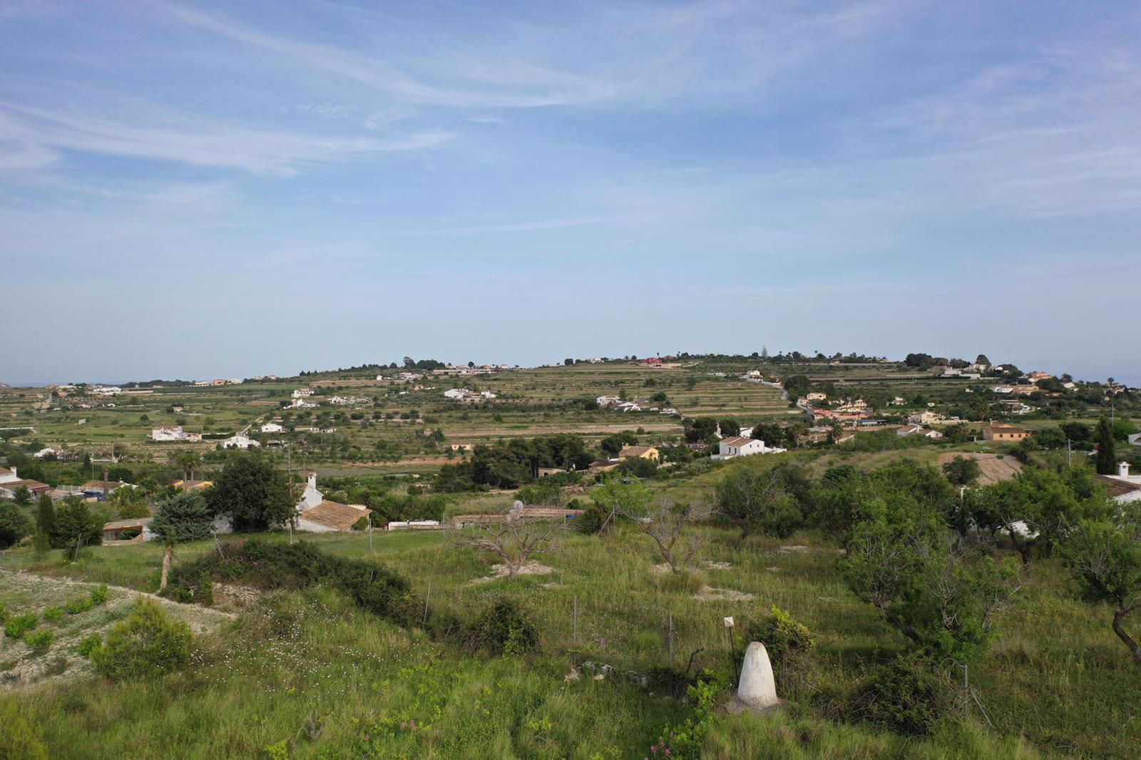 Vista panorámica de los alrededores naturales con colinas abancaladas y vegetación mediterránea autóctona bajo un cielo despejado.