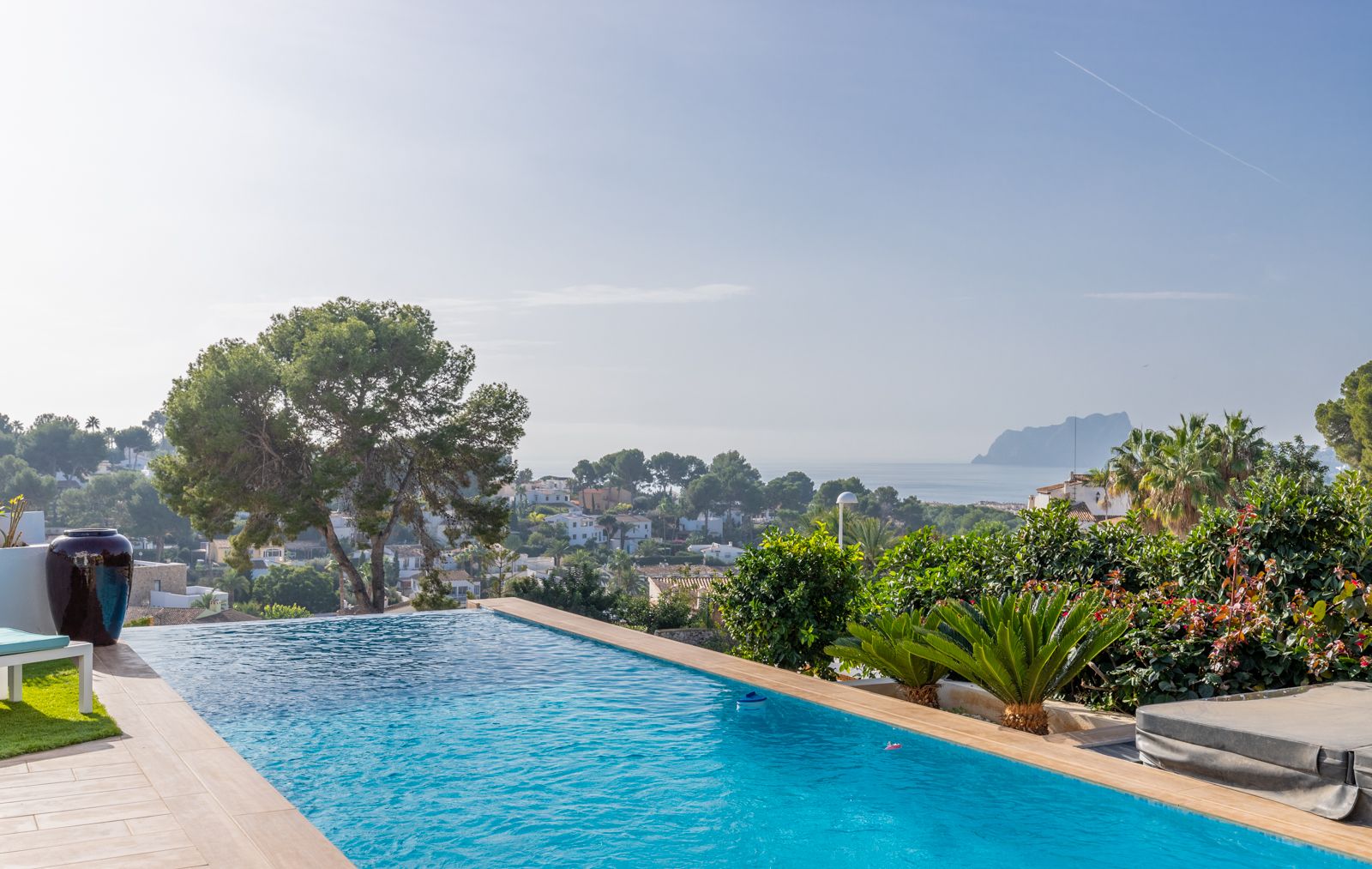 Piscina infinita con vistas panorámicas al mar Mediterráneo y al Peñón de Ifach, rodeada de una terraza de gres porcelánico y vegetación autóctona.