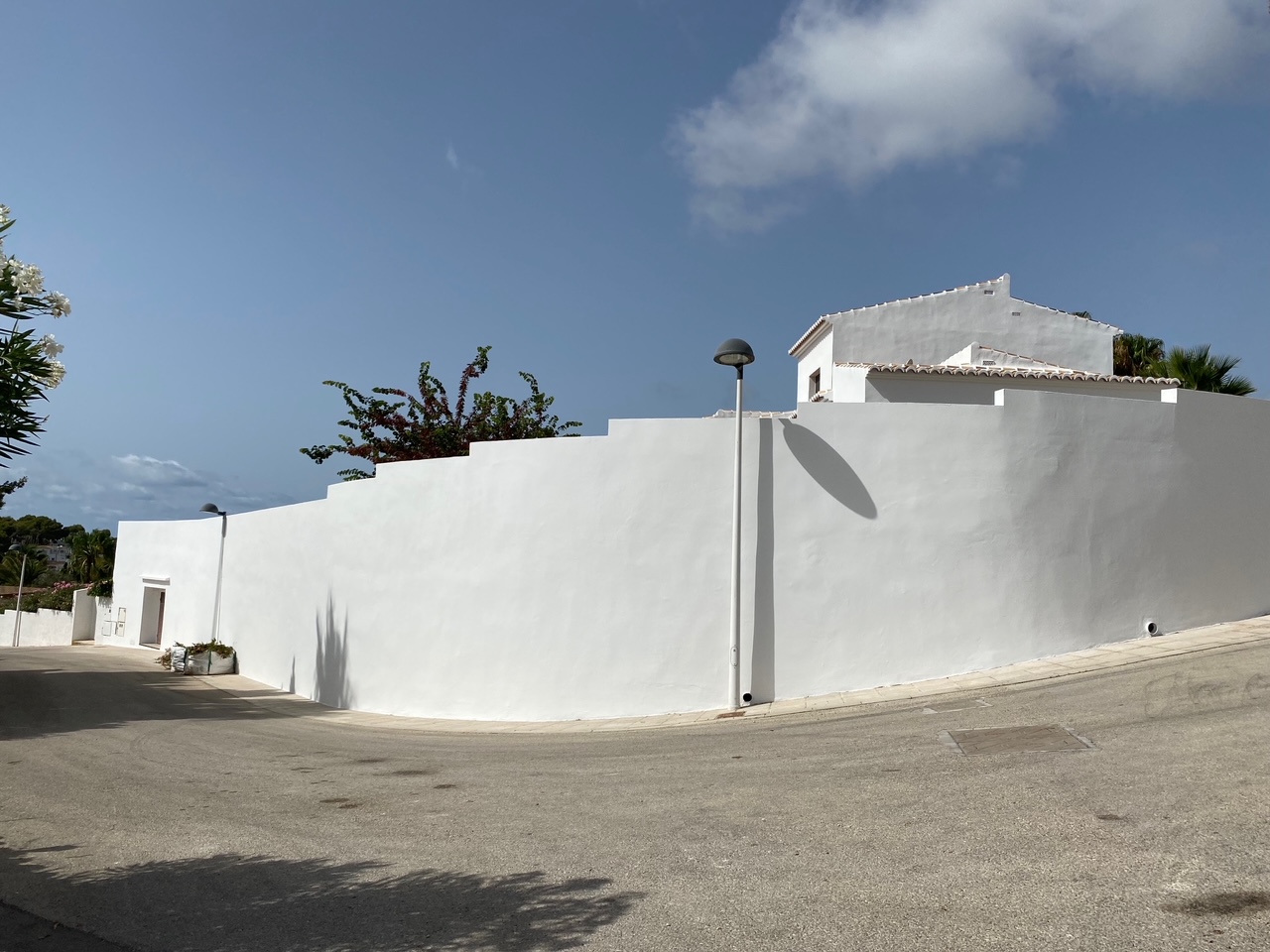 Vista exterior de la propiedad destacando el muro perimetral blanco con diseño escalonado, que garantiza privacidad absoluta desde la calle en esta zona de Moraira.