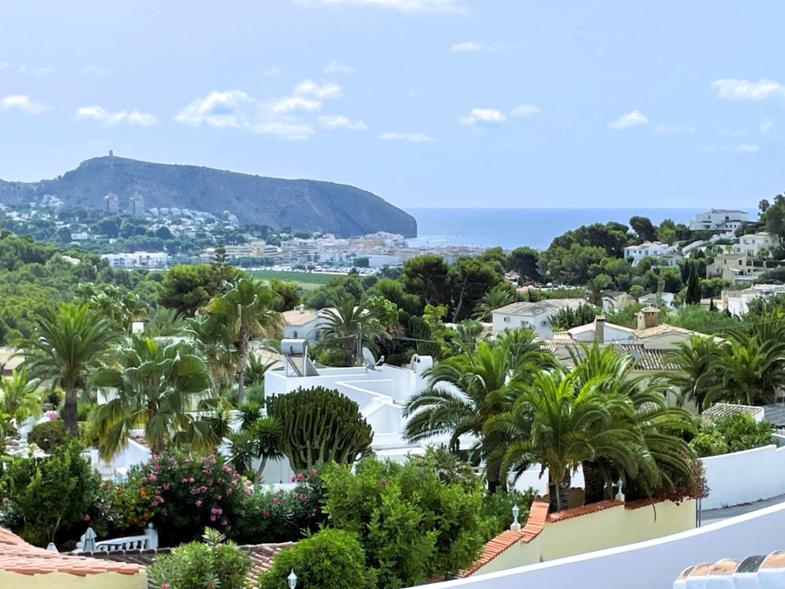 Vistas panorámicas abiertas hacia la costa de Moraira, el mar Mediterráneo y el emblemático Cap d'Or, rodeadas de vegetación autóctona y palmeras.