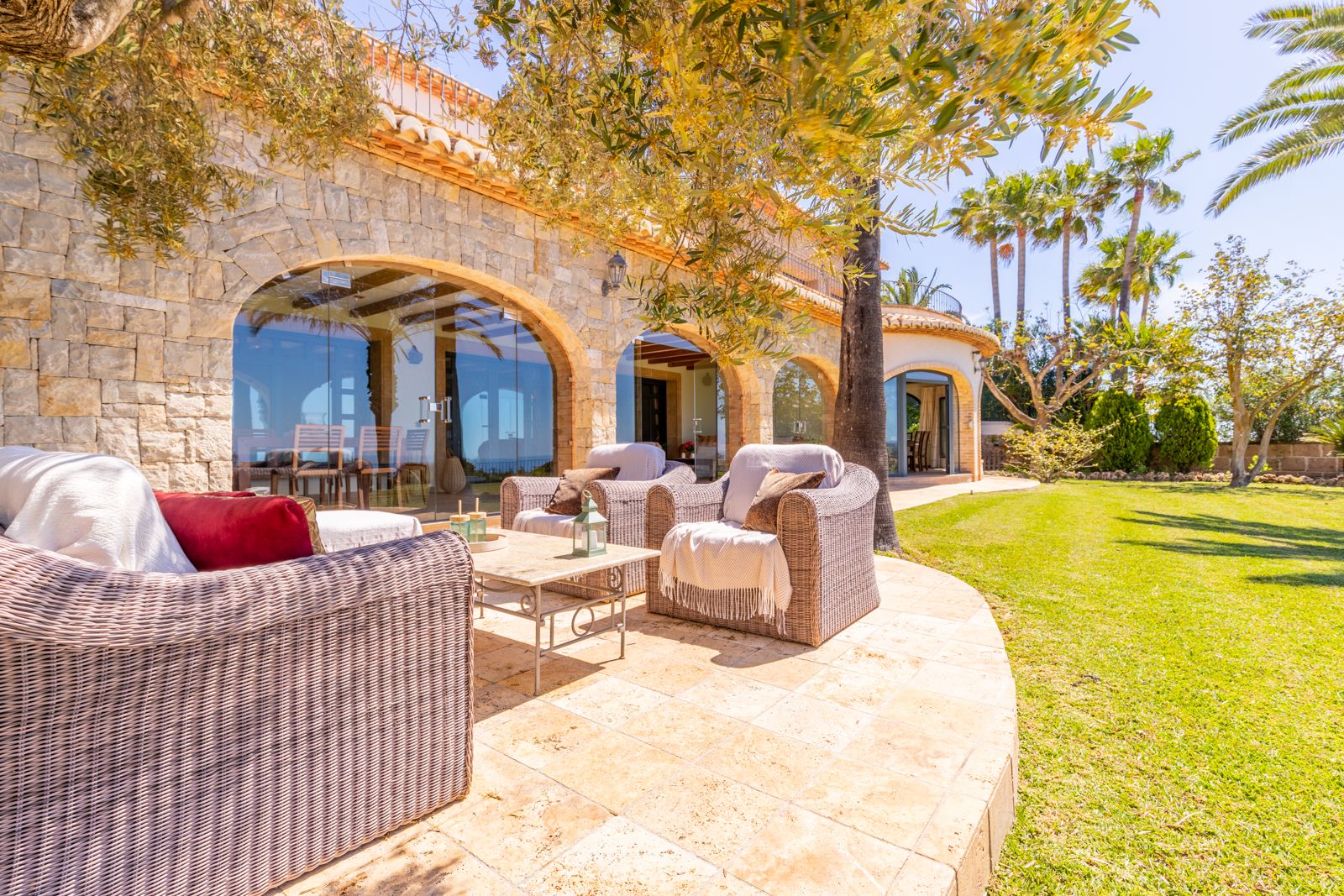 Terraza con sillones de mimbre y arcos de piedra con vistas al jardín.