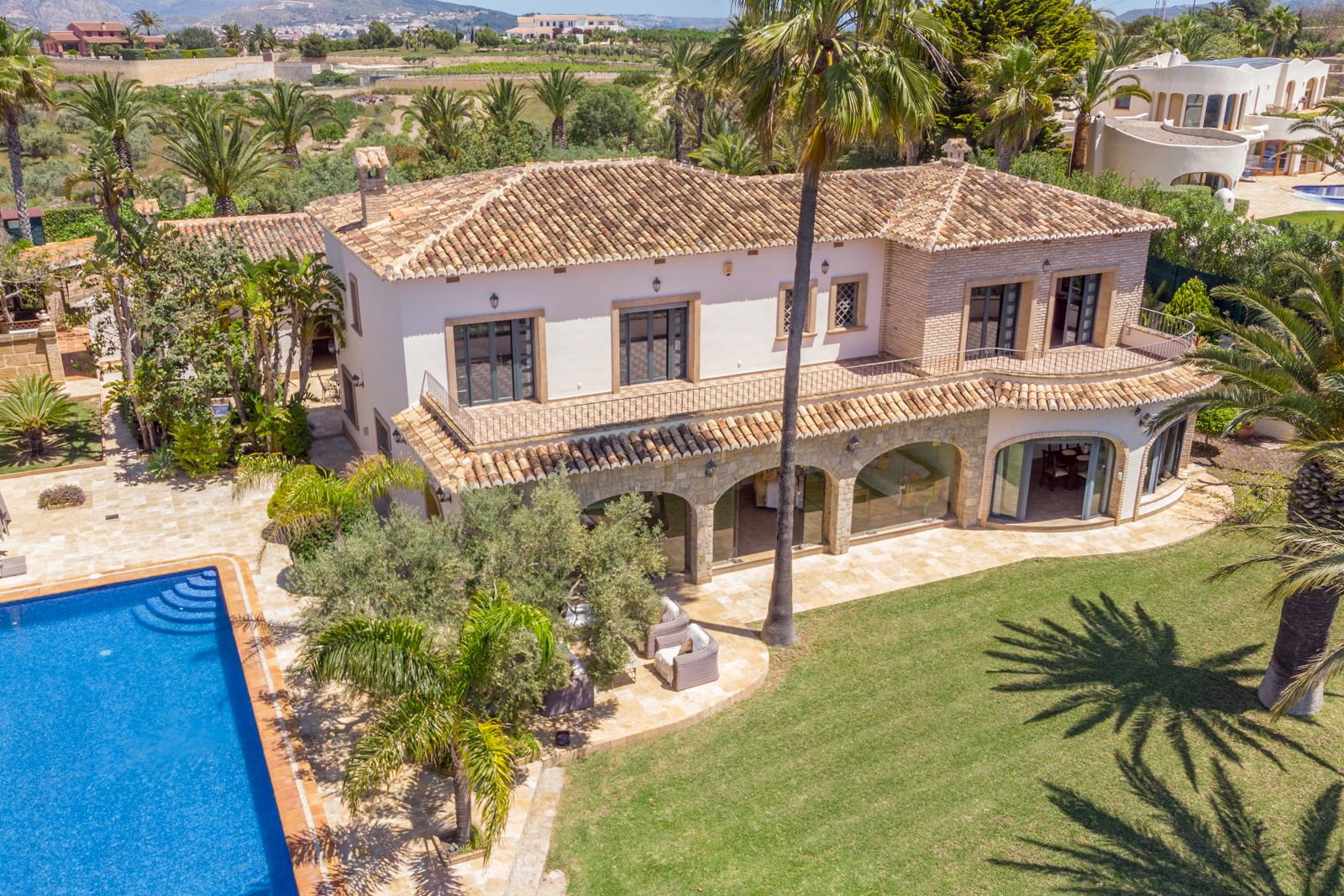 Vista aérea de la finca con piscina, jardín y terraza cubierta con arcos de piedra.
