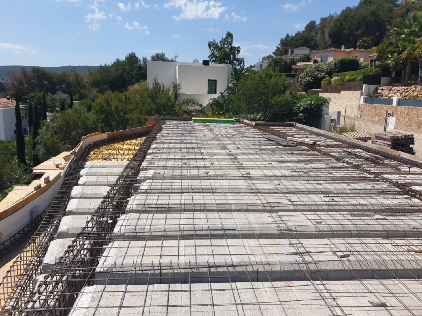 Estado actual de la construcción mostrando el forjado unidireccional con viguetas, bovedillas y armadura de acero sobre una parcela elevada en Jávea.
