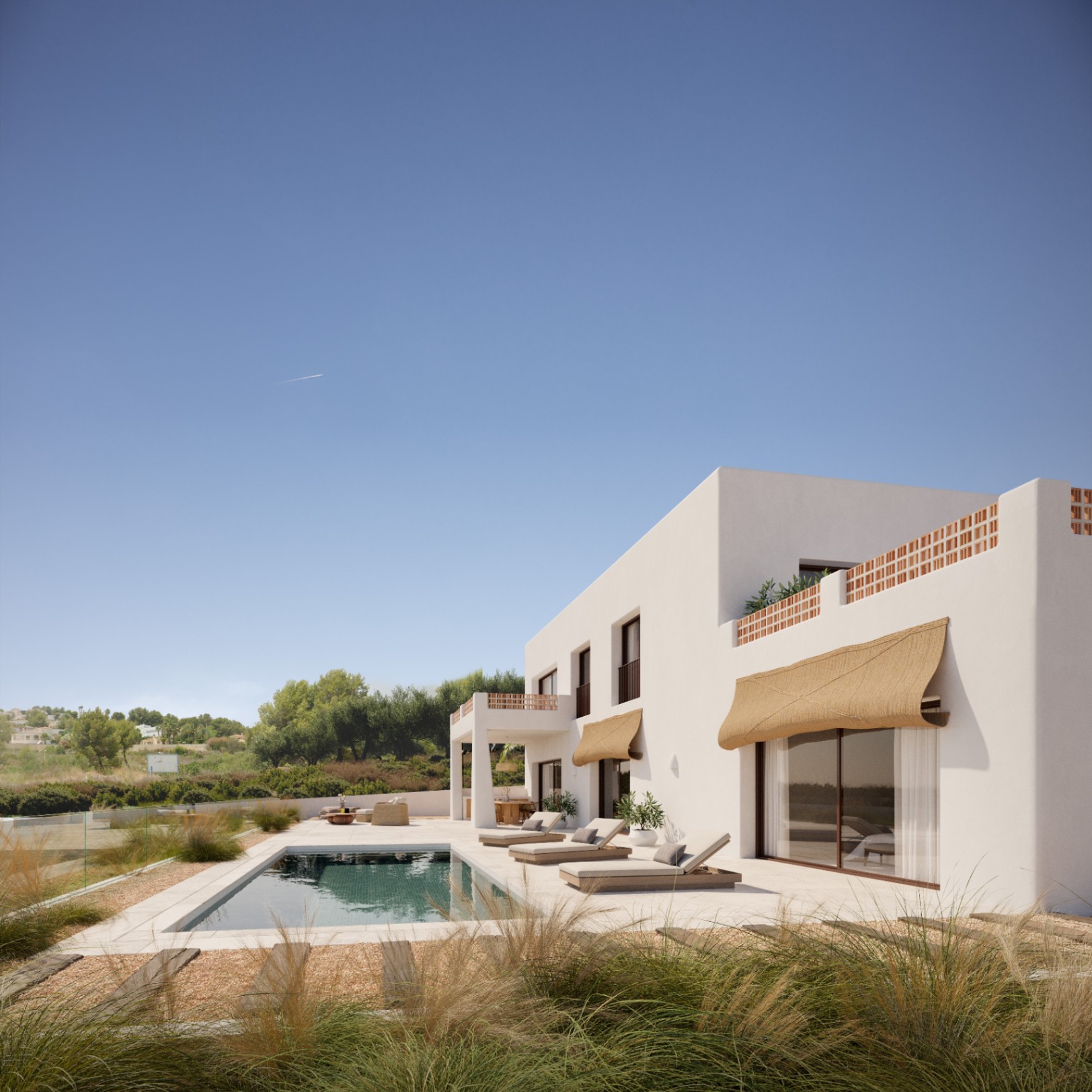 Exterior de la villa con piscina rectangular, terraza de piedra y toldos de fibra natural. La fachada blanca destaca por sus celosías de terracota y amplios ventanales.
