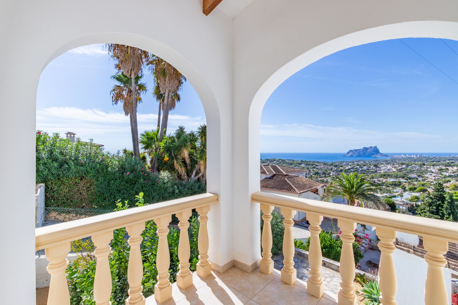Terraza cubierta con arcos blancos y balaustrada clásica, ofreciendo vistas panorámicas al mar Mediterráneo y al emblemático Peñón de Ifach.