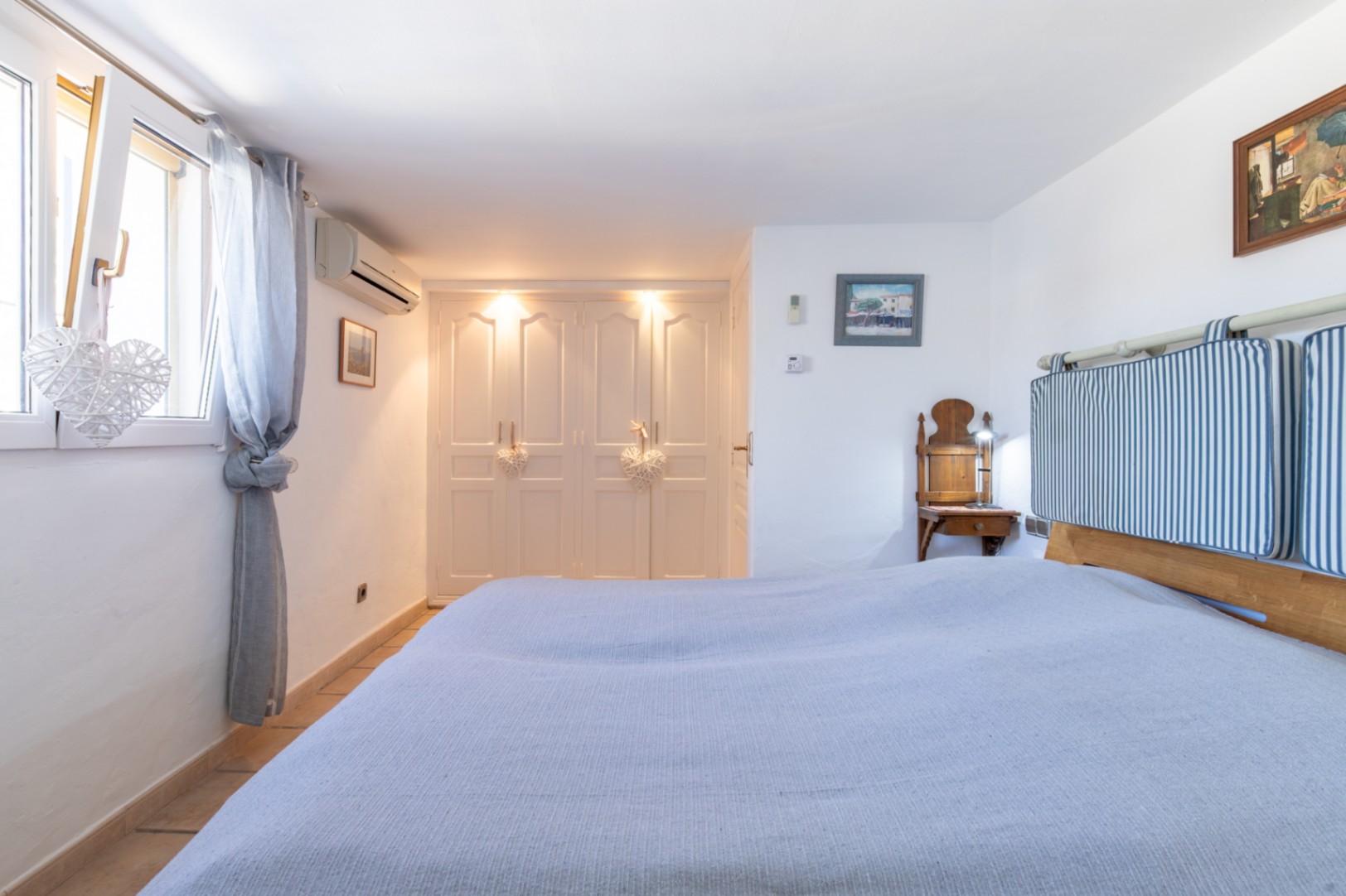 Dormitorio con armarios empotrados de puertas blancas, iluminación integrada, aire acondicionado y ventanas de doble acristalamiento que aportan luz natural.