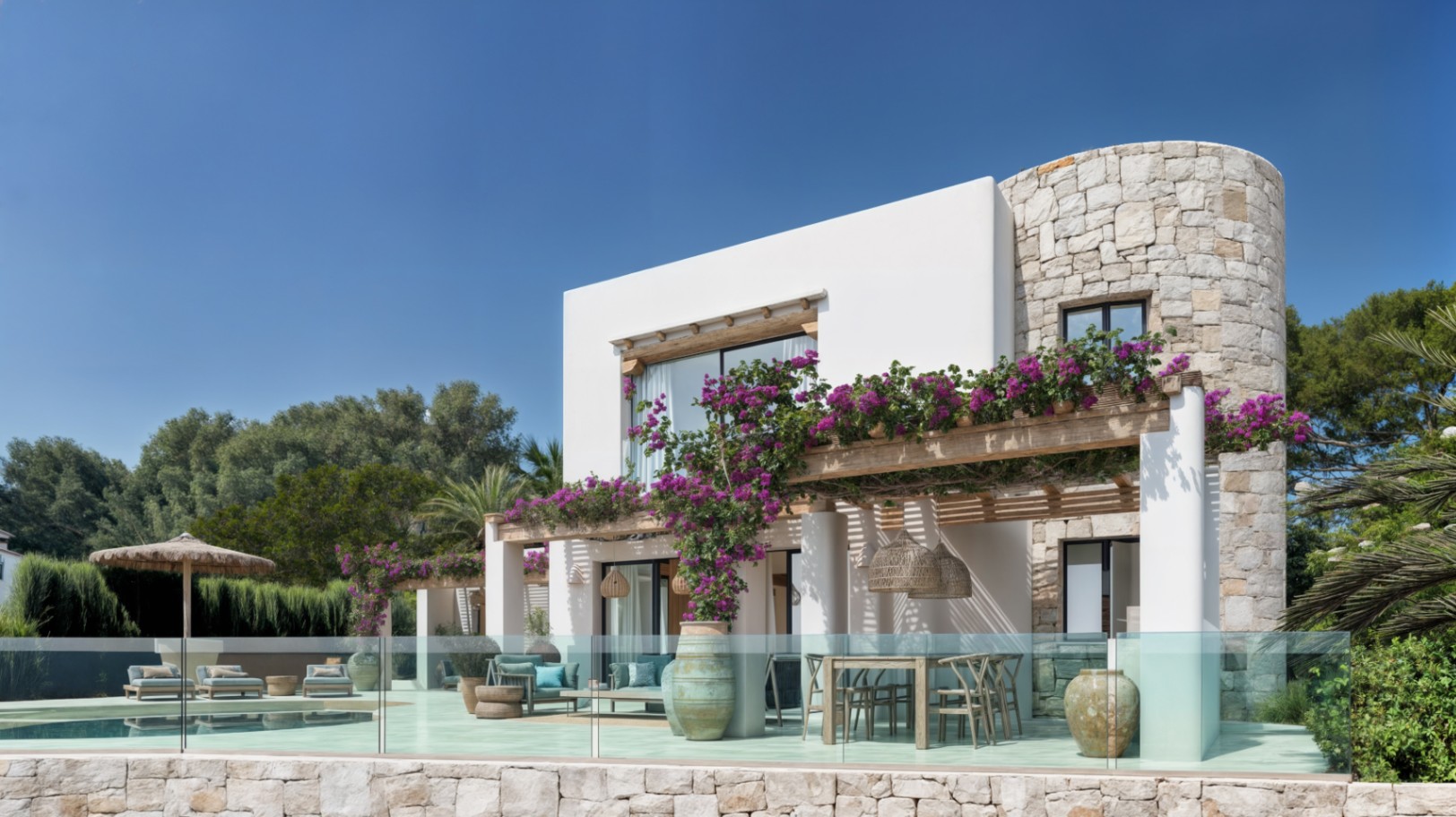 Exterior de villa ibicenca con muros de piedra natural, pérgola de madera con buganvillas y terraza con comedor frente a la piscina y barandilla de cristal.