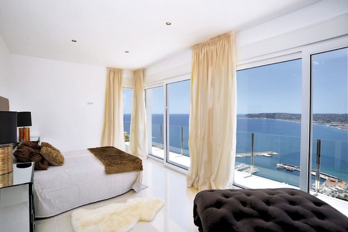 Suite con ventanales de suelo a techo, vistas panorámicas al puerto de Jávea y el Mediterráneo. Suelos pulidos, iluminación empotrada y acceso directo a la terraza.