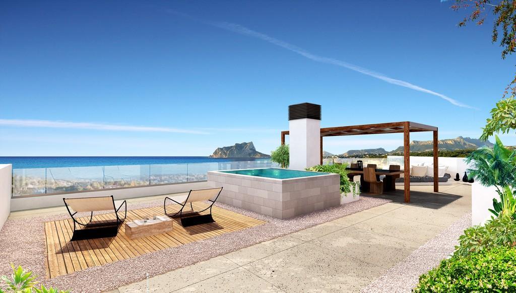 Terraza en la azotea con piscina elevada, zona de comedor bajo pérgola de madera y vistas despejadas al mar Mediterráneo y al Peñón de Ifach.
