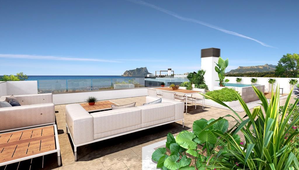 Terraza solárium con zona de estar, comedor exterior y barandillas de cristal que ofrecen vistas panorámicas al mar Mediterráneo y al Peñón de Ifach.