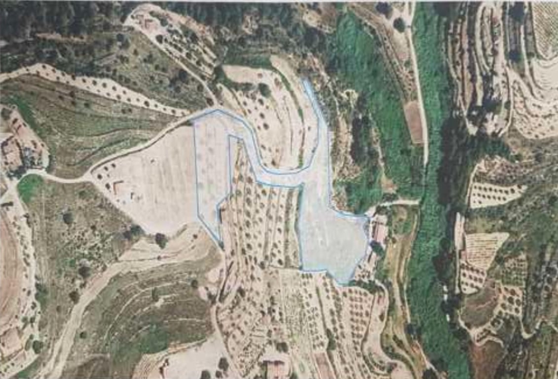 Vista aérea perimetrada de la parcela rústica, destacando su topografía aterrazada y la distribución de árboles frutales en un entorno natural.