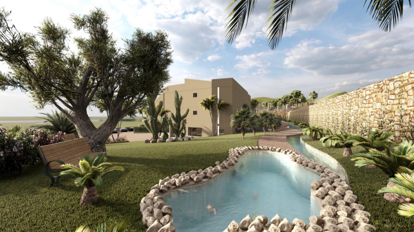Jardines paisajísticos con estanque de piedra, senderos sinuosos y vegetación mediterránea que rodea el edificio principal bajo una iluminación natural clara.
