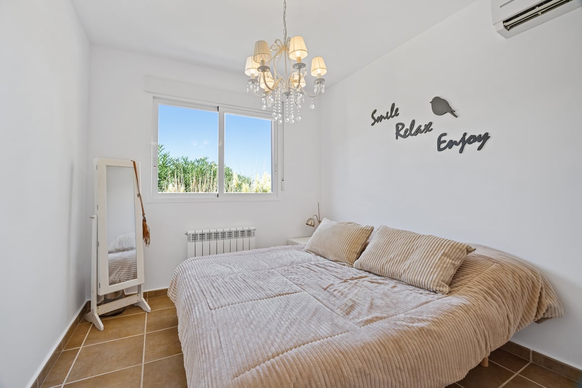 Dormitorio luminoso con suelos de gres, aire acondicionado split y radiador. Incluye ventana de doble acristalamiento con vistas al exterior y una lámpara de araña clásica.