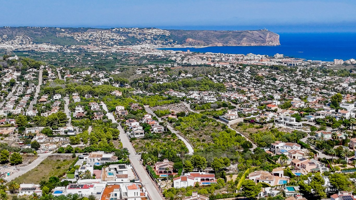 Vista aérea panorámica de Jávea que muestra la proximidad al mar Mediterráneo, el Cabo de San Antonio y las zonas residenciales rodeadas de vegetación autóctona.