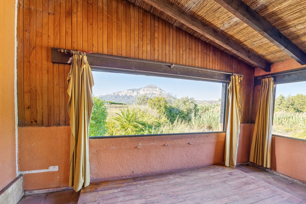 Espacio interior con techos de madera y cañizo que enmarca vistas despejadas al macizo del Montgó a través de un gran ventanal horizontal.