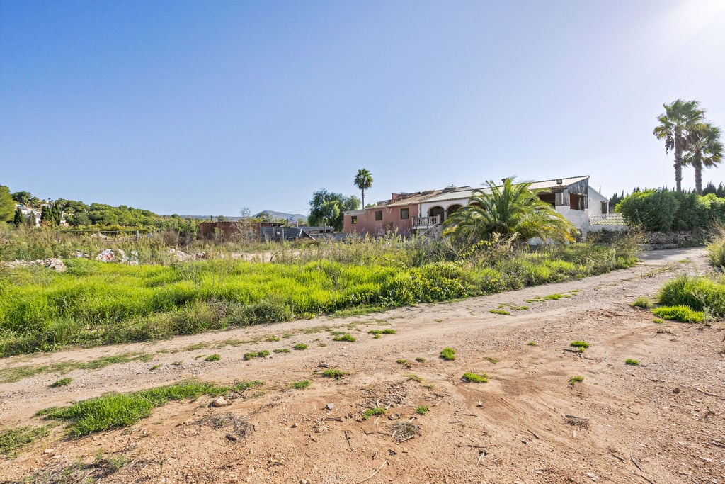 Vista exterior de la amplia parcela rústica con una construcción tradicional de estilo mediterráneo, arcos de naya y vegetación autóctona en Jávea.