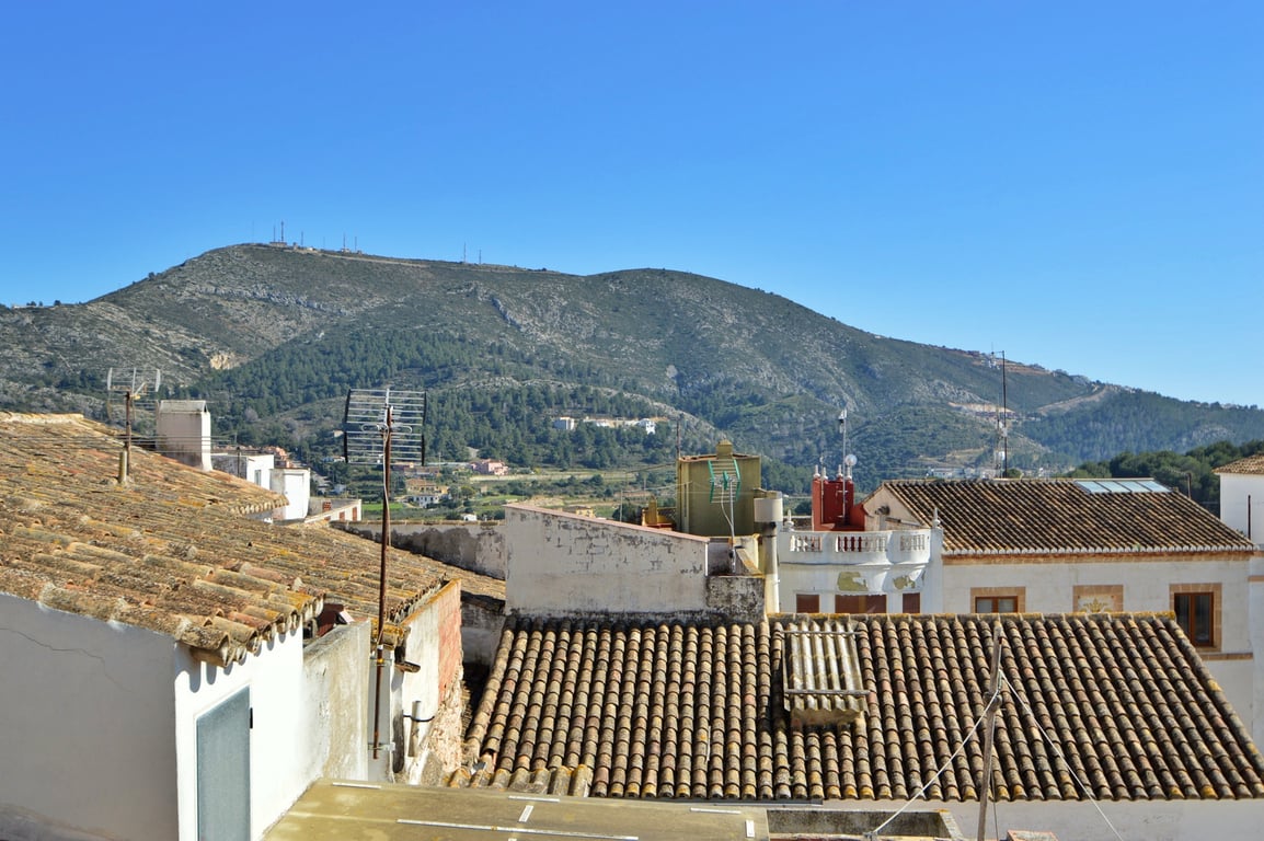 Vistas panorámicas desde la terraza hacia las montañas circundantes y los tejados tradicionales del pueblo bajo un cielo despejado.