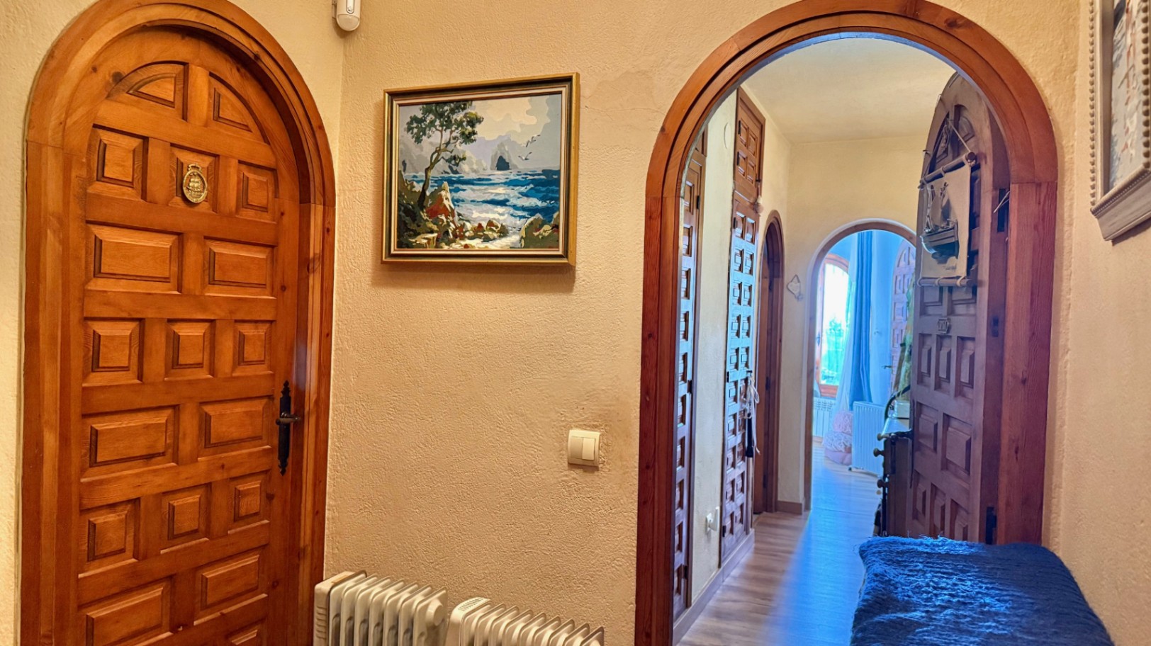 Pasillo con puertas de madera maciza en arco y armarios empotrados. Dispone de calefacción central por radiadores y suelos laminados claros.