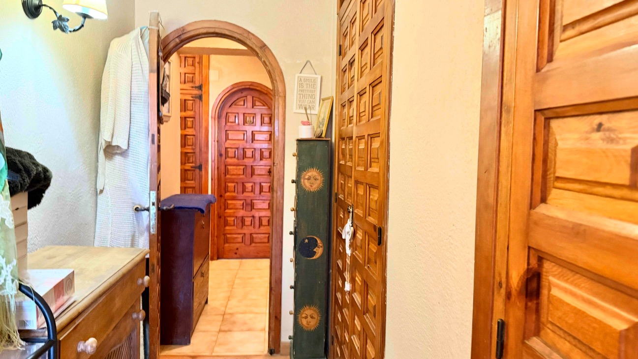 Pasillo distribuidor con suelos cerámicos, armarios empotrados de madera maciza y arcos de medio punto que conectan las estancias principales.